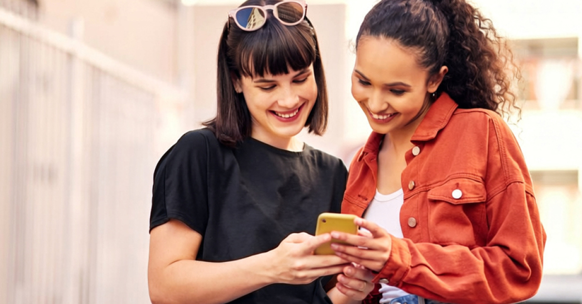 Two customers comparing mobile plans on a smartphone as Moose Mobile users explore switching to Yomojo and staying on the Optus network.