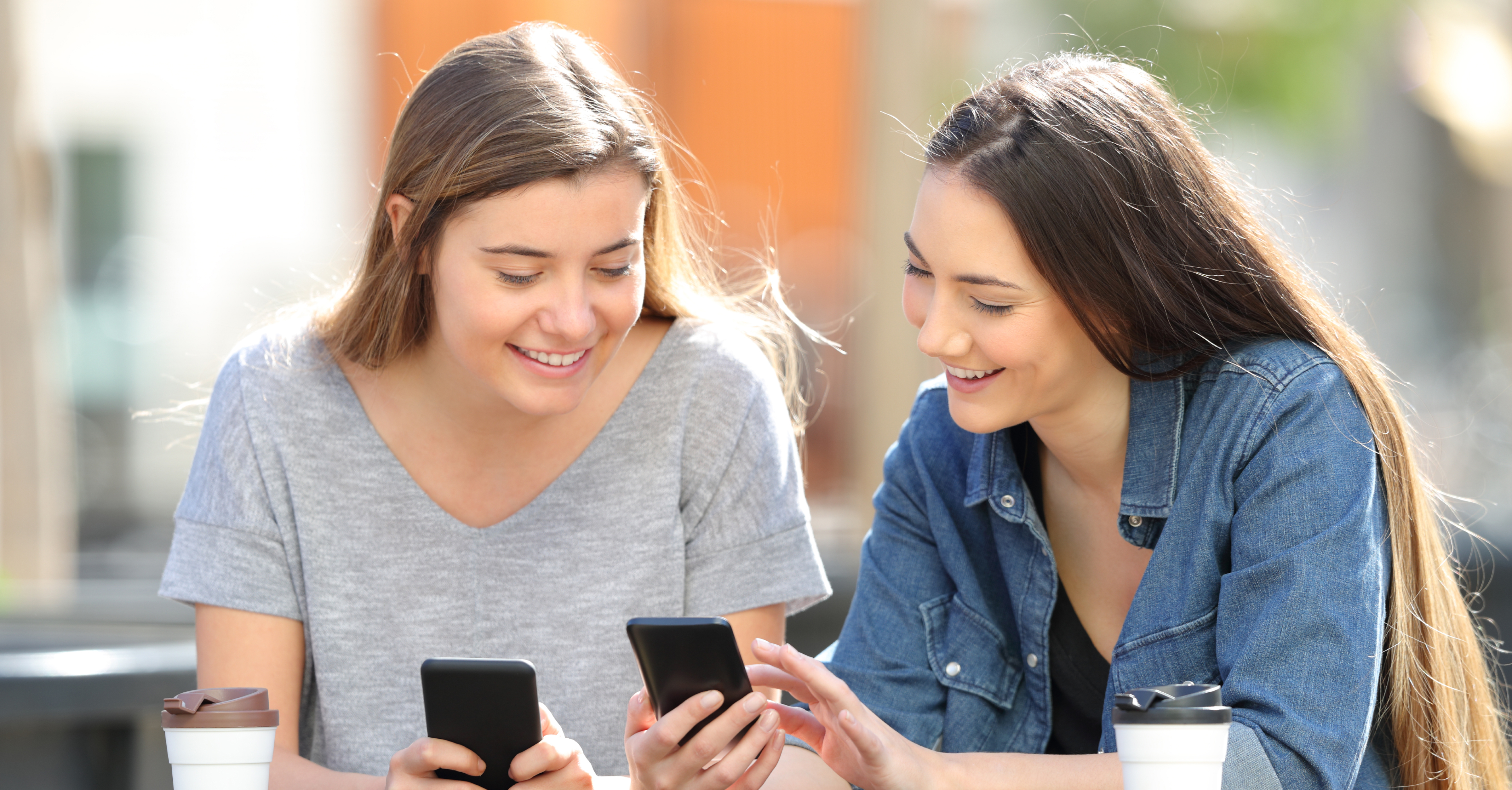 Two people using smartphones while comparing mobile broadband and data SIM plans in Australia.