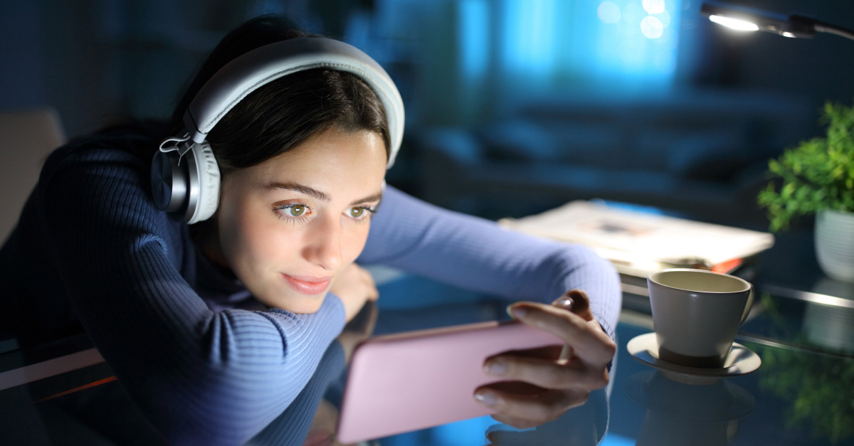 Woman using a smartphone at home while streaming online, illustrating tips for managing devices on a Wi-Fi network.