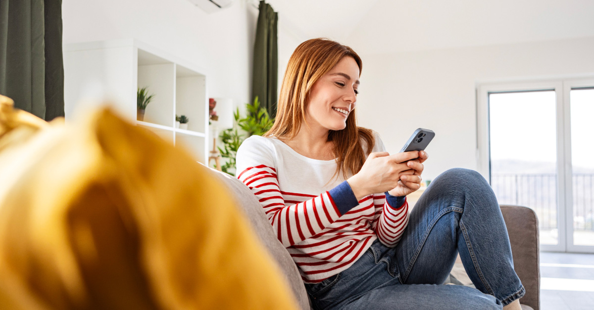 Woman using a smartphone in a living room with strong Wi-Fi connectivity in an nbn®-connected home.